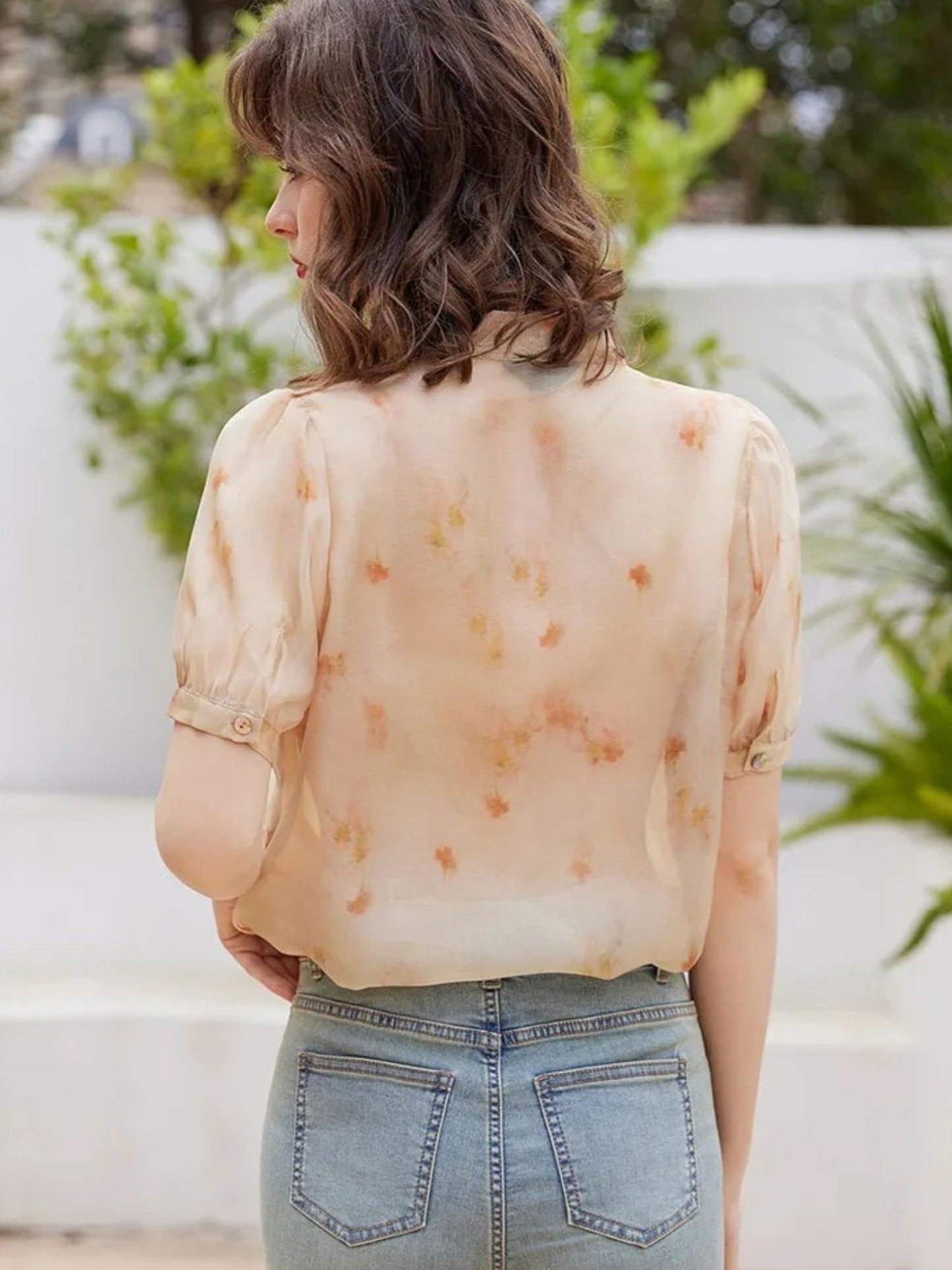 Bakfra bilde av lys oransje bluse stylet med jeans og hestehale