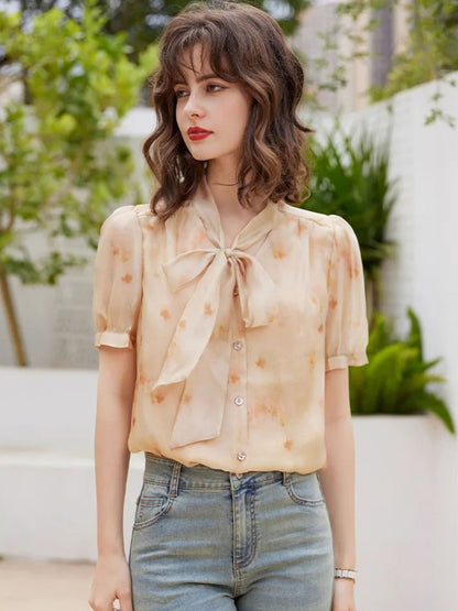 Modell i lys oransje bluse med print og blå jeans, smilende