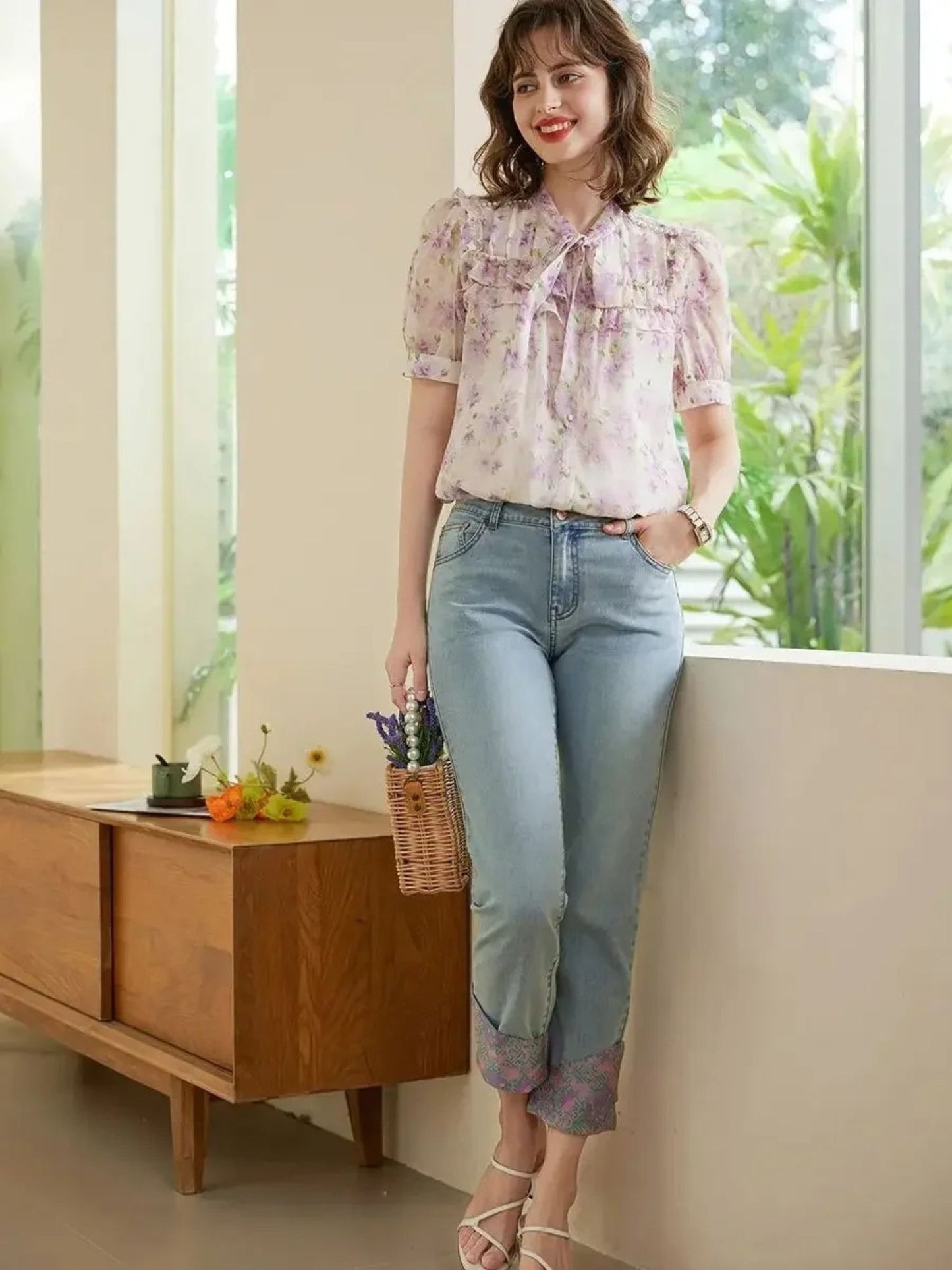 Modell står i rosa bluse med blomsterprint og knelang denimskjørt