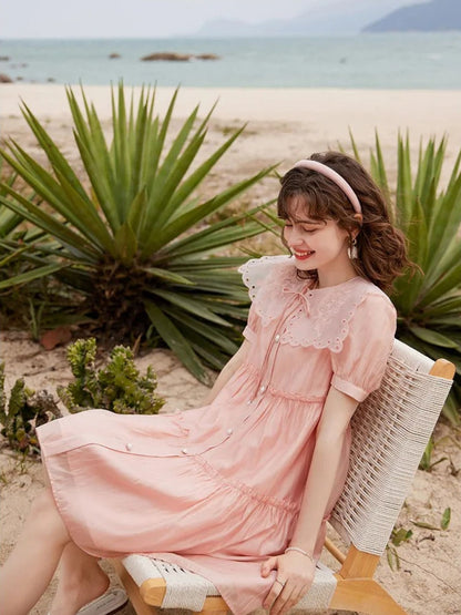 Modell i rosa lagdelt kjole, smiler og ser bort fra kamera