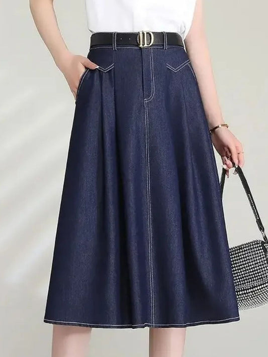 Model wearing high-waisted A-line denim skirt with front pleats and black belt
