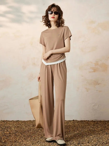 Modell smilende i beige sett med runde solbriller og flate sko