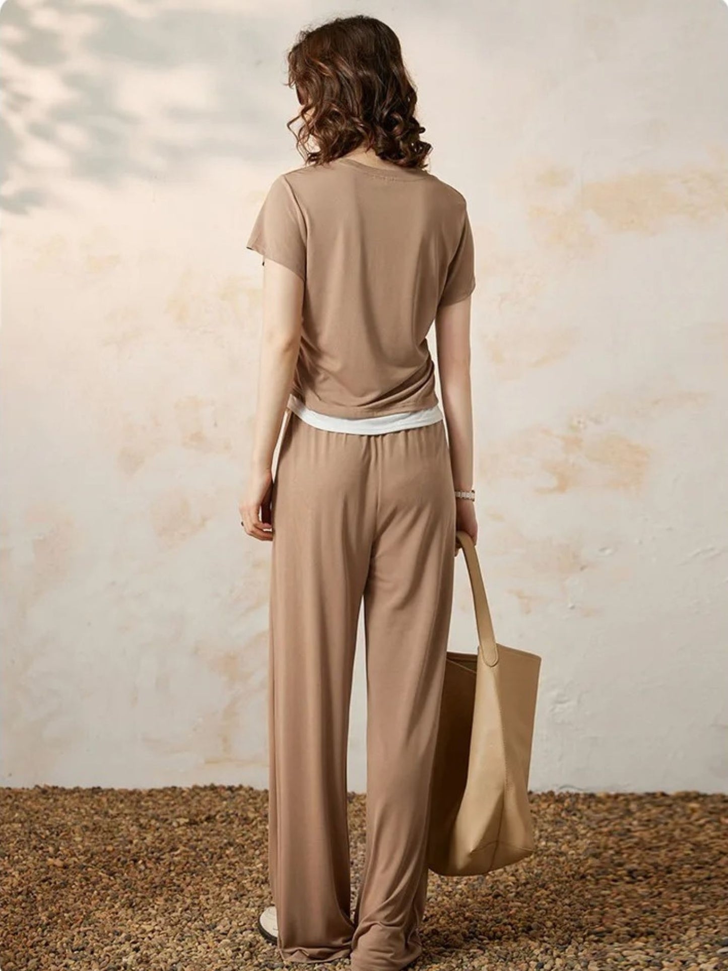 Bakfra bilde av beige topp og vide bukser med hvit kant