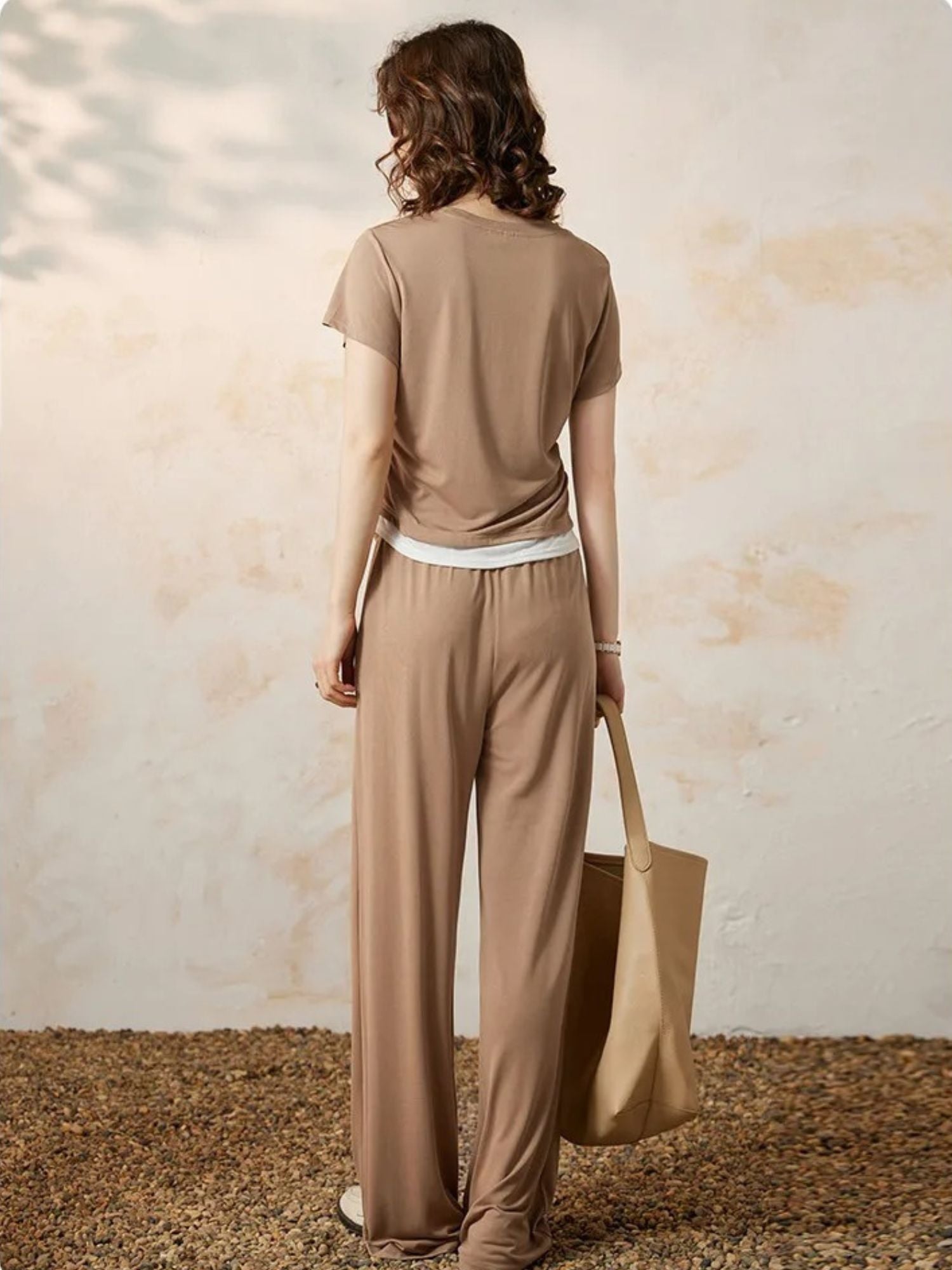 Bakfra bilde av beige topp og vide bukser med hvit kant