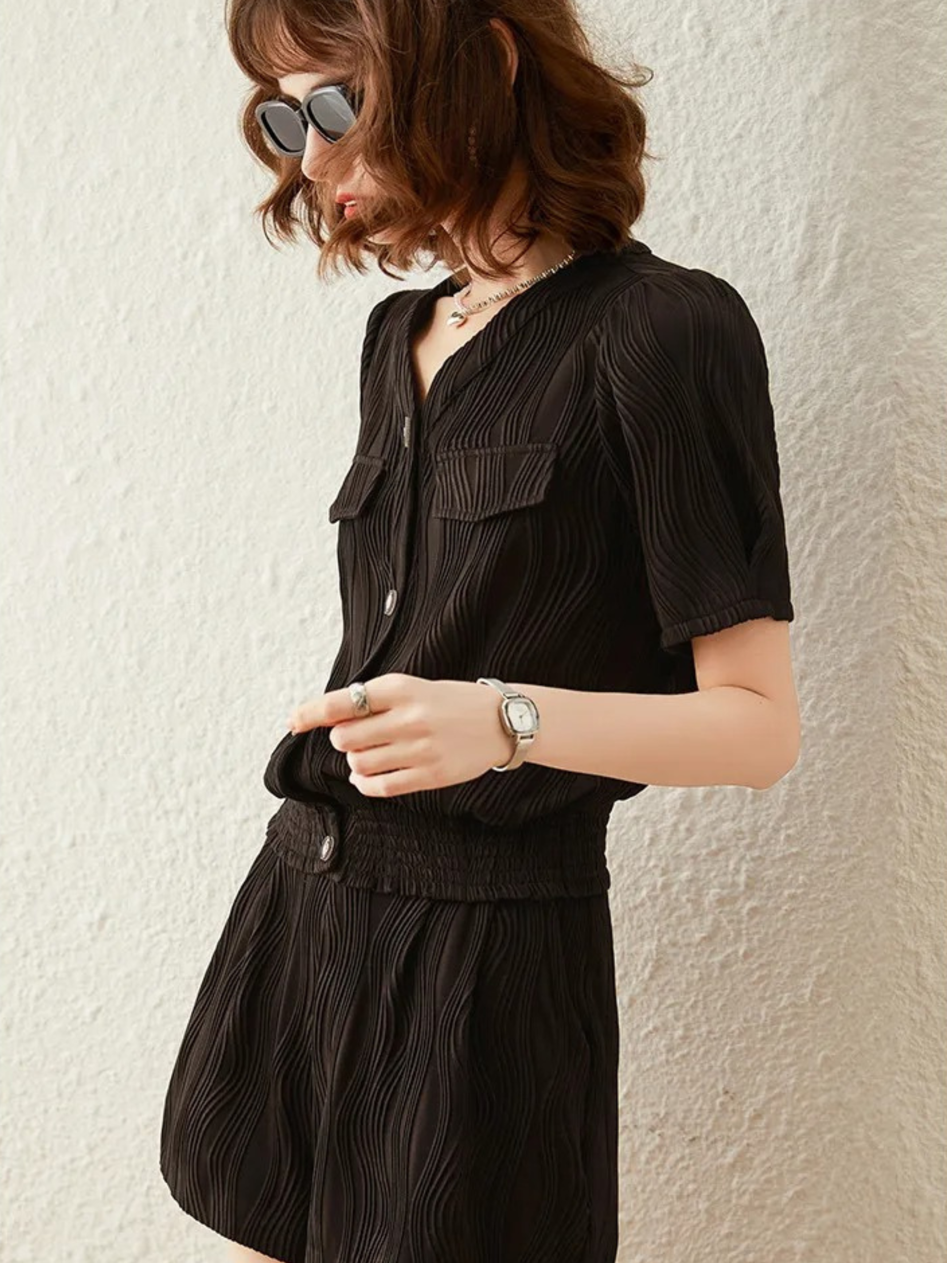 Sidebilde av svart knappet jumpsuit med korte ermer og elastisk midje

